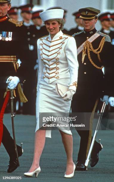 Diana, Princess of Wales, wearing a white military suit with gold majorette drum frogging and epaulettes designed by Catherine Walker and a white hat...