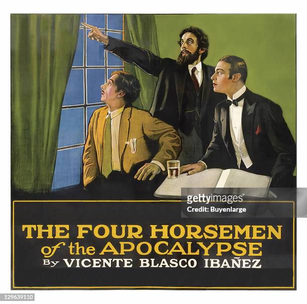 Three men look and point out a window on a poster that advertises the movie 'The Four Horsemen of the Apocalypse,' 1921.