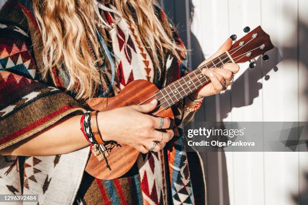 a beautiful woman in an ecuadorian poncho and cowboy hat holds a ukulele guitar. hippie style. real people. extraordinary appearance. red lipstick. romance and creativity. - ukulele foto e immagini stock