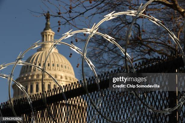 Concertina razor wire tops the 8-foot 'non-scalable' fence that surrounds the U.S. Capitol the day after the House of Representatives voted to...