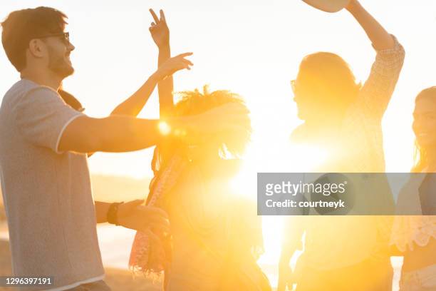 gruppe von freunden tanzen und feiern am strand bei sonnenaufgang / sonnenuntergang. - party stock-fotos und bilder