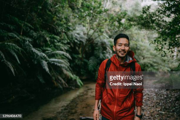 japanese man hiking in rainforest, okinawa, japan - raincoat stock pictures, royalty-free photos & images
