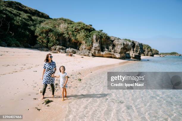 young girl and her mother walking on beach, japan - okinawa islands stock pictures, royalty-free photos & images