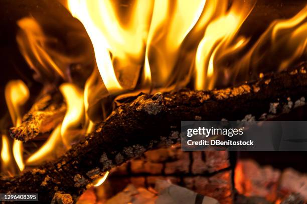 logs of firewood burning in the fire of a fireplace with embers - wood burning stove stock-fotos und bilder