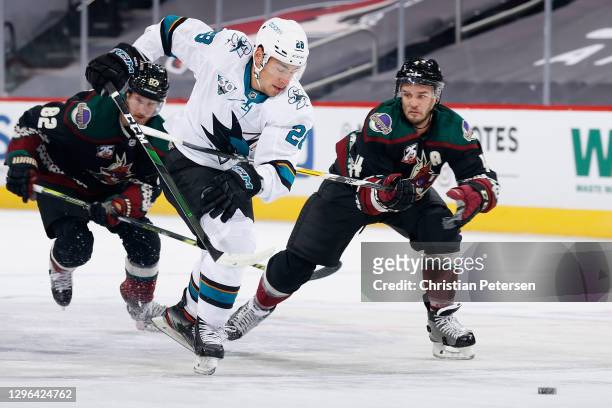 Timo Meier of the San Jose Sharks is hooked by Niklas Hjalmarsson of the Arizona Coyotes as he attempts to skate with the puck during the first...