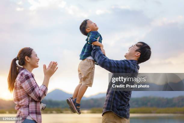 happy asian family holidays during joyful father, mother and son hiking and raise son to sky along summer sunset . happy family travel in nature in holiday, summer and vacation. - happy holidays family stock pictures, royalty-free photos & images