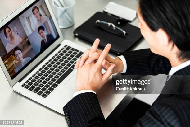 スーツを着たビジネスマンがオフィスでオンライン会議をしています - リモート ストックフォトと画像