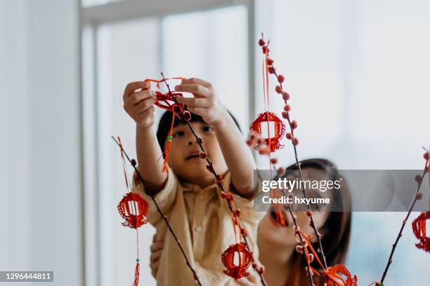asiatiska unga kinesiska pojke hjälpa mamma att hänga kinesiska nyåret dekoration - östasiatiskt ursprung bildbanksfoton och bilder