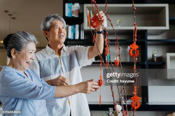 senior asian chinese couple decorating house for chinese new year - 70 year male stock pictures, royalty-free photos & images