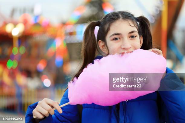 girl eating cotton candy in amusement park - cotton candy stock pictures, royalty-free photos & images