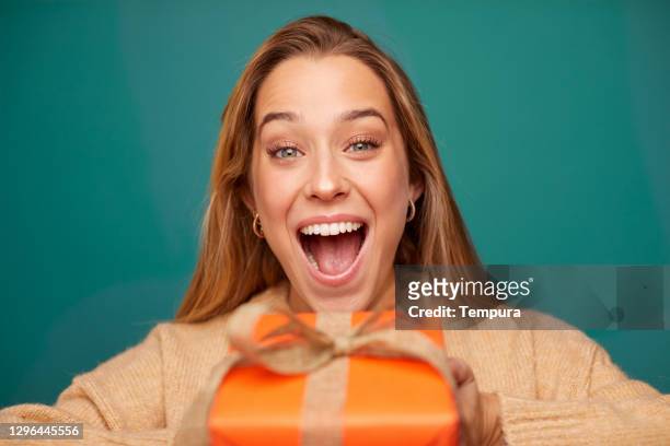 sorpresa giovane donna in possesso di un regalo di natale. - surprise gift foto e immagini stock