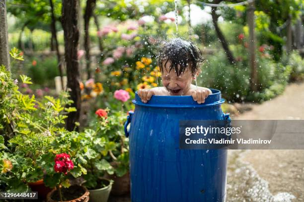 small boy taking bath in a water tank in the garden - standing water stock pictures, royalty-free photos & images