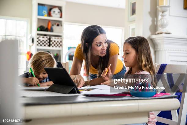 mother working from home and homeschooling children - boy using ipad imagens e fotografias de stock