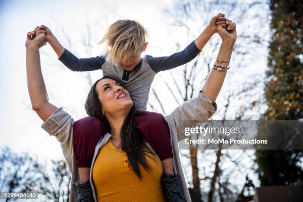 young boy riding on mother's shoulders outdoors - maman photos et images de collection