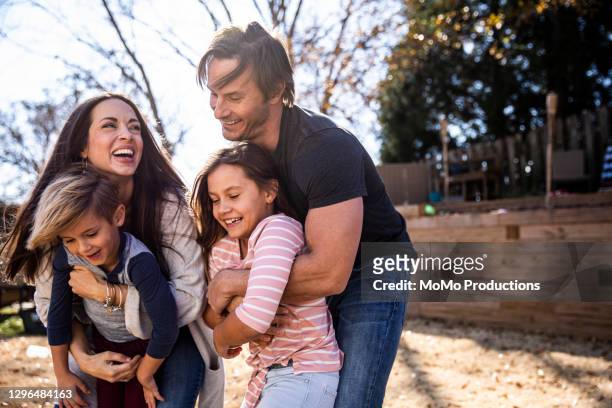 portrait of family in backyard of home - family of four in front of house stock-fotos und bilder