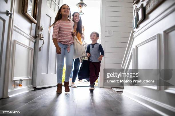 mother and children carrying groceries into home - family in front of house stock-fotos und bilder