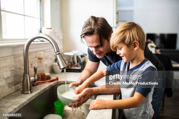 father and son doing dishes in kitchen - children housework stock pictures, royalty-free photos & images