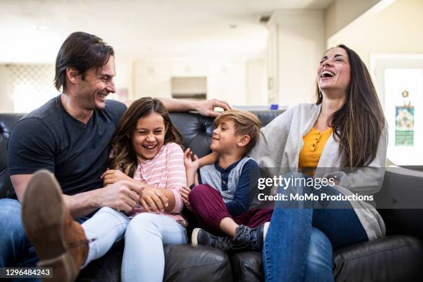 portrait of family on sofa at home - four people smiling foto e immagini stock