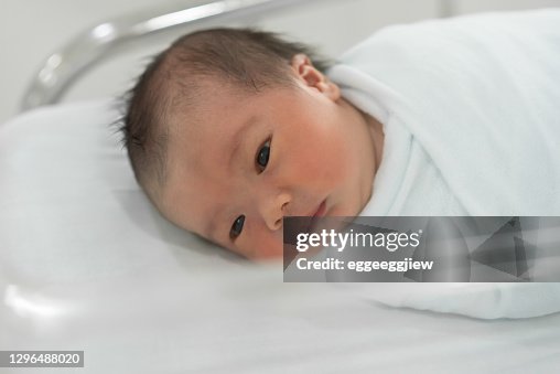 Asian Newborn baby lying on white bed in the hospital. Asian Newborn baby lying on white bed in the hospital.