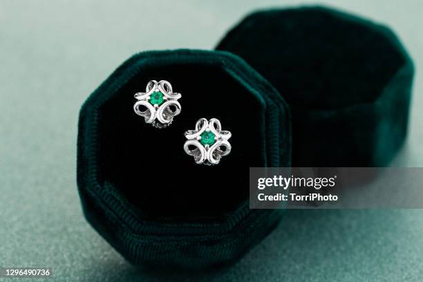close-up of silver earrings with emeralds on green background - emerald gemstone stockfoto's en -beelden