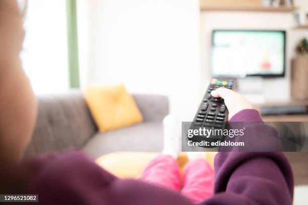 watching cartoon on tv remote control in hand - zapping stock pictures, royalty-free photos & images