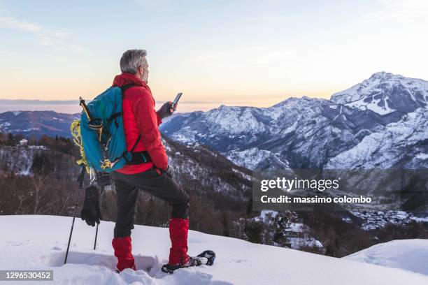 hiker with snowshoes on mountain using smartphone apps - switzerland alps stock pictures, royalty-free photos & images