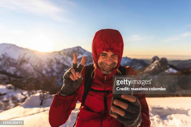 hiker on mountain during video call with smartphone - freizeitaktivität stock-fotos und bilder
