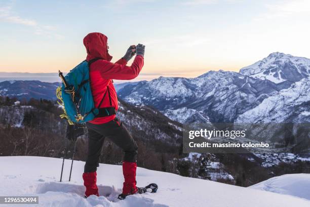 hiker with snowshoes take a pics to mountain with smartphone apps - sneeuwschoen stockfoto's en -beelden