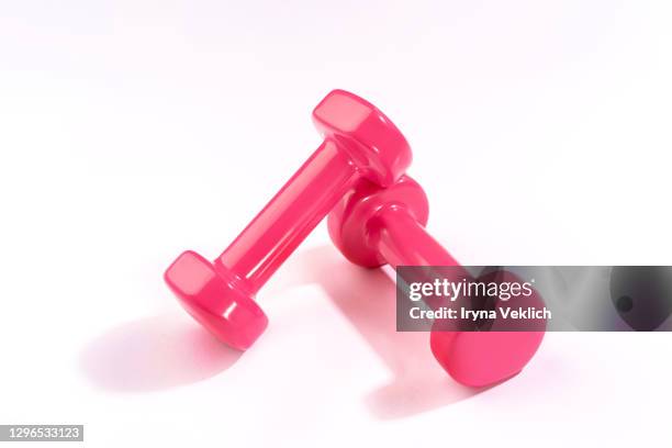 sport lifestyle concept with pink dumbbells on white background. - gewichten stockfoto's en -beelden