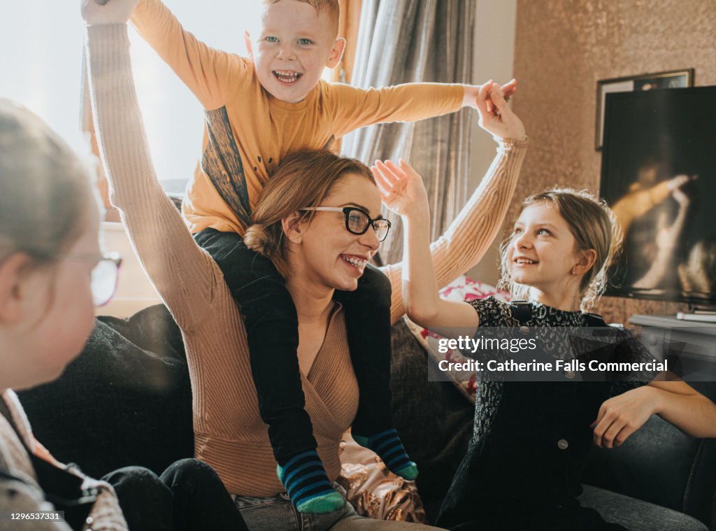 Mother with son on her shoulders, is surrounded by her Happy Children