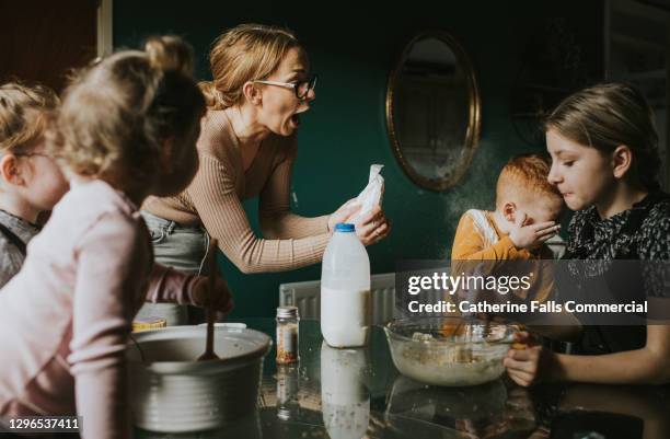 mother looks surprised as son recoils after batter splatters on him - milk family stockfoto's en -beelden