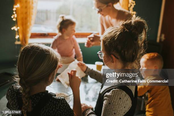 children baking at a table with mum supervising. daughters in foreground. - stay at home mum スト�ックフォトと画像