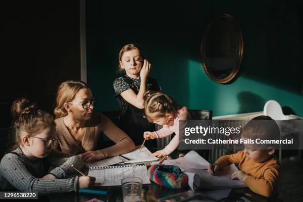 mother attempting to home school her 4 children - busy mum mess stock-fotos und bilder