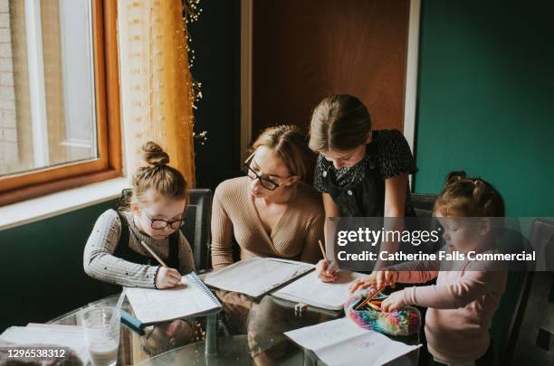 mother homeschooling her 3 daughters - instruction à domicile photos et images de collection