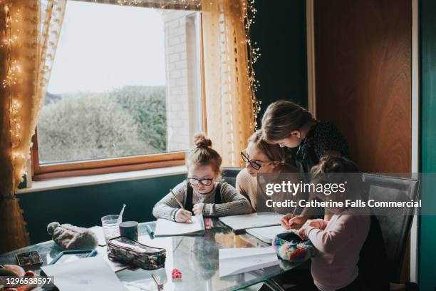 mother homeschooling her 3 daughters - child pulling hair stock pictures, royalty-free photos & images