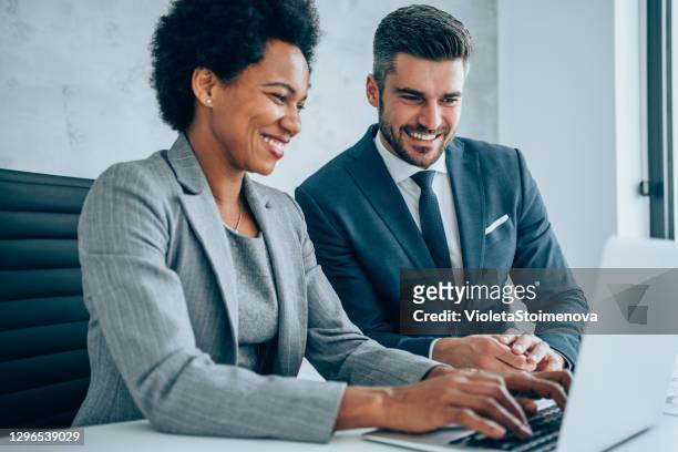 confident business partners working on laptop in office. - businesswear stock pictures, royalty-free photos & images
