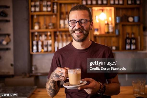 mann hält tasse kaffee in bar - bar man t shirt stock-fotos und bilder