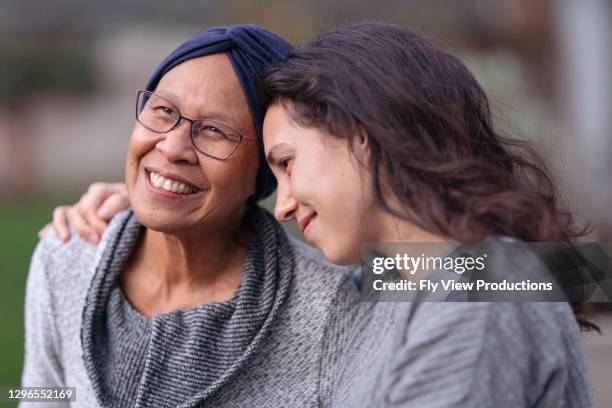 beautiful hawaiian senior woman with cancer embracing her adult daughter - pacific islander stock pictures, royalty-free photos & images