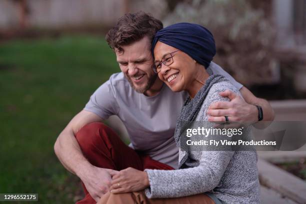 belle femme aînée hawaïenne avec le cancer embrassant son fils adulte - leucémie photos et images de collection