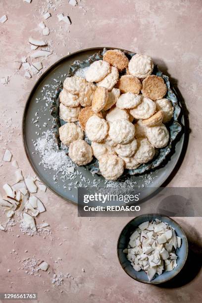 Homemade coconut gluten free cookies with coconut flakes on ceramic plate over pink texture background. Flat lay. Copy space.