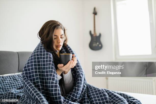 zieke vrouw die in bed met hoge koorts ligt. koude griep en migraine - cold indoors stockfoto's en -beelden