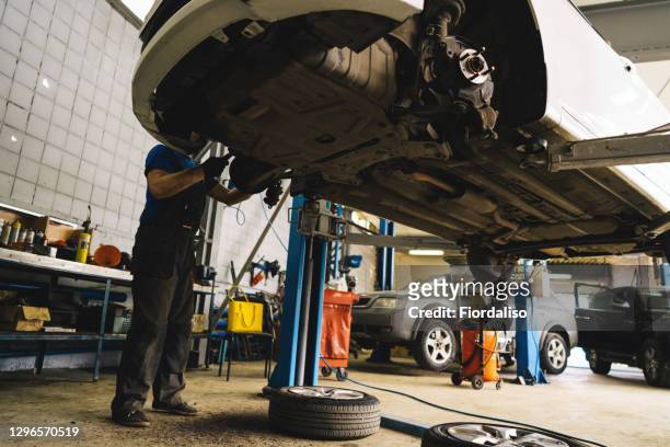 engine oil drain unit. car on a lift in a car service. - drain inspection stock-fotos und bilder