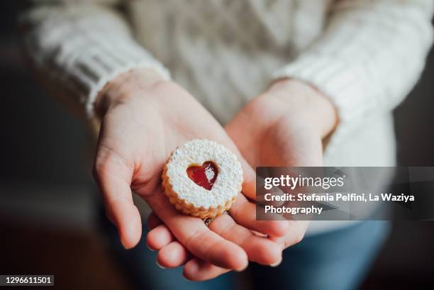 close up of hands cupped showing a linzer cookie. - dessert lifestyle stock pictures, royalty-free photos & images