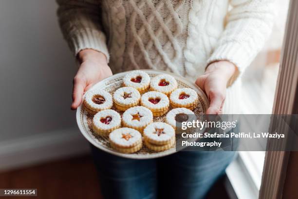 hands holding a plate with homemade linzer cookies - butter tart stock pictures, royalty-free photos & images