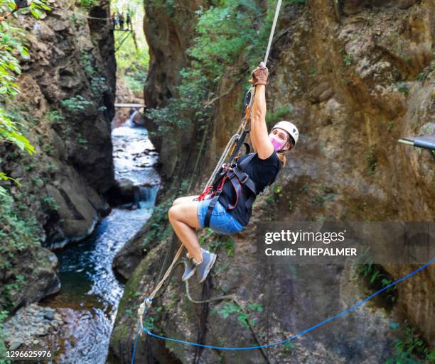 woman hanging from rope swing on canopy tour central america - costa rica zipline stock pictures, royalty-free photos & images