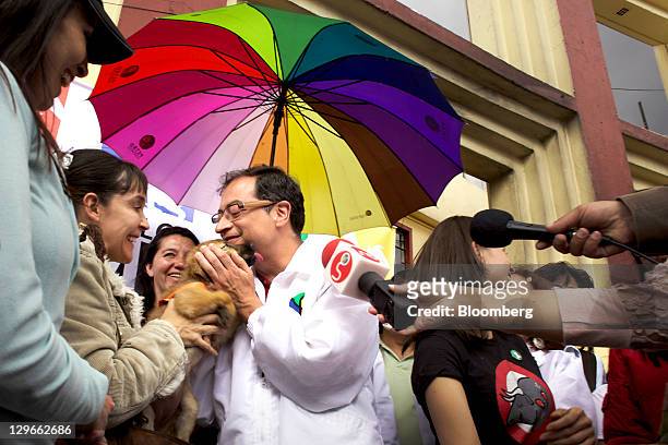 Gustavo Petro, candidate for mayor of Bogota, greets a woman and her puppy at a campaign event in Bogota, Colombia, on Saturday, Oct. 15, 2011....