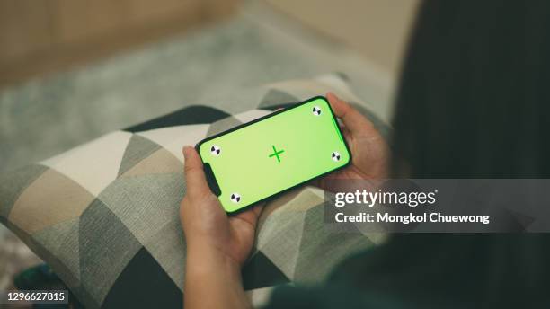 close-up woman looking and using smartphone on green screen chroma key in living room at home - horizontaal stockfoto's en -beelden