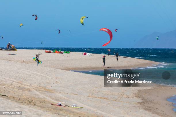 Kitesurfers prepare their equipment on the beach while others navigate the waters of the Gulf of California during a day amid Covid-19 pandemic at...