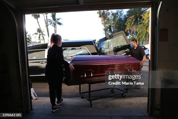 Embalmer and funeral director Kristy Oliver and funeral attendant Sam Deras load the casket of a person who died after contracting COVID-19 into a...