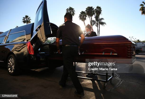 Embalmer and funeral director Kristy Oliver and funeral attendant Sam Deras load the casket of a person who died after contracting COVID-19 into a...